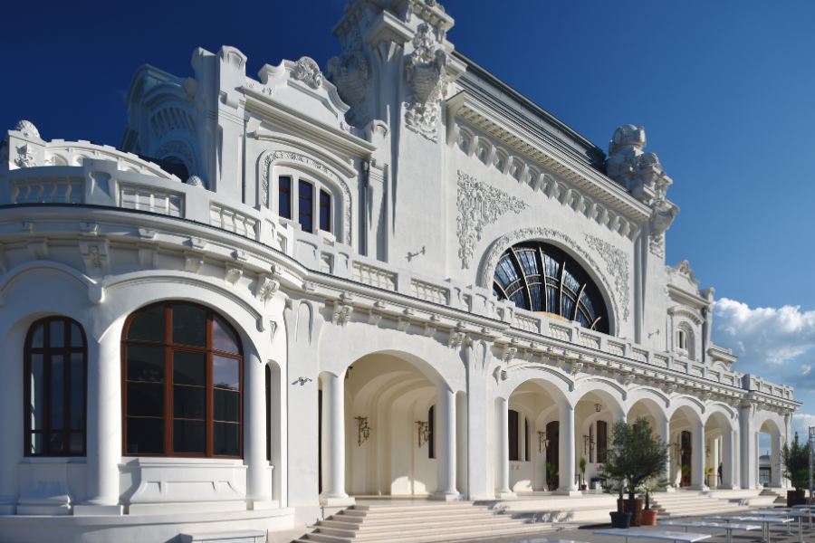 White ornate building with arched colonnade and decorative details against a clear blue sky.